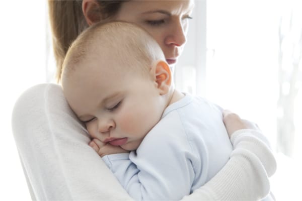 Mother cuddling her baby with infant constipation