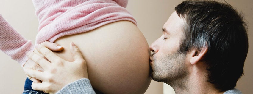 Father kissing pregnant mum's baby bump