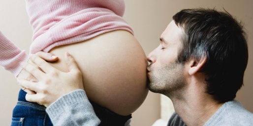 Father kissing pregnant mum's baby bump