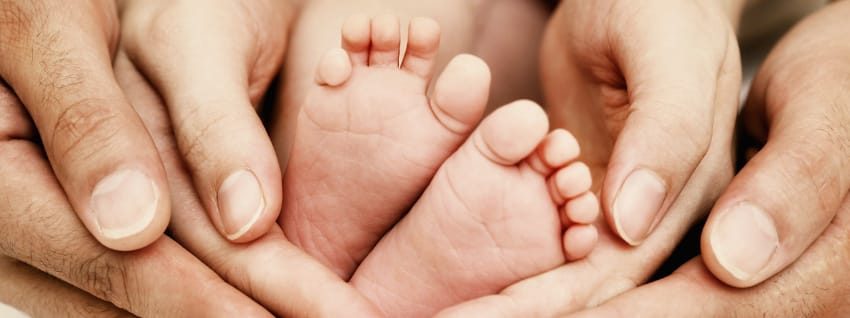 Adult hands supporting baby feet