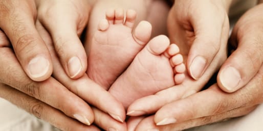 Adult hands supporting baby feet