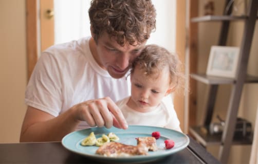 Father feeding toddler solid foods