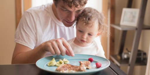 Father feeding toddler solid foods