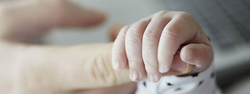 Baby holding parent finger