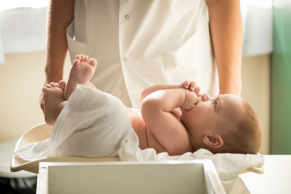 Healthcare professional measuring weight and height of a baby