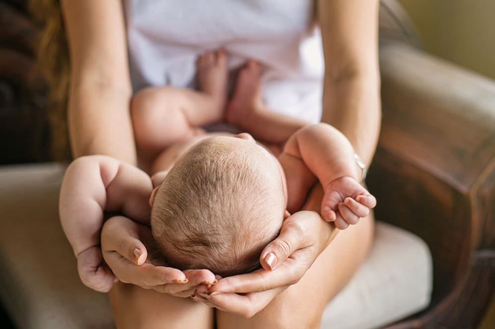Mother cradling baby's head on her lap